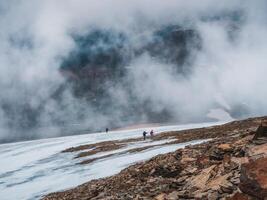 Tourists come to top of misty snowy hill. teamwork and victory, teamwork of people in difficult conditions. Difficult climb to the top of the mountain. photo