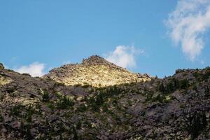 Sunlight glides along the slopes of majestic high and sharp mountains from each side. photo