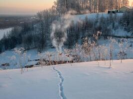 Foot path through deep snow to a hut in a snow-covered ravine. photo