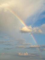 Beautiful rainbow in the sky over clouds. Vertical view. photo