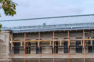 Repair of the roof of the building, galvanized iron sheets, wooden scaffolding at the facade of the building. photo