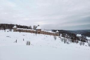 Old wooden fortress on a snow-covered hill photo