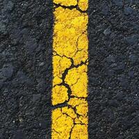 Cracked yellow line on asphalt surface revealing wear and tear in a parking lot during daylight hours photo