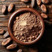 Rich cocoa powder in a bowl surrounded by cocoa beans on a wooden surface photo