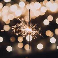 Sparkler shining brightly against a blurred background of luminous lights during a festive celebration at night photo