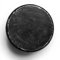 Hockey puck resting on a flat surface with visible scratches and wear indicating frequent use photo