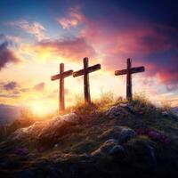 Three wooden crosses stand on a hill at sunset surrounded by colorful clouds and gentle hills in the background photo