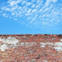Brick wall under a blue sky with textured clouds in a clear daytime setting photo