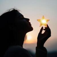 Woman holding star-shaped decoration against sunset silhouette near horizon while appreciating beauty of nature photo