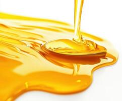 Golden honey drizzling from a spoon onto a glossy surface in a bright setting photo