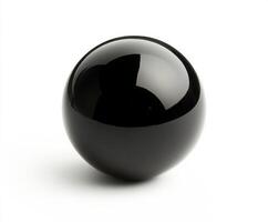 Smooth black billiard sphere sits on a white surface reflecting light in a minimalist setting photo