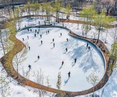 Winter ice skating activity at a community rink surrounded by trees in a serene park setting photo