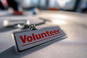 Close-up of a volunteer badge with bold red text reflecting in sunlight photo