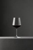 Elegant red wine glass on surface and dark backdrop minimalist aesthetic with sleek reflections and shadows photo