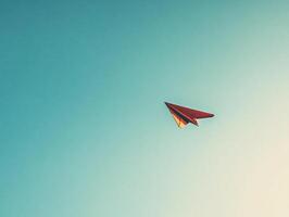 Minimalist red paper plane soaring in clear blue sky symbolizing freedom, ambition, and simplicity in a vibrant composition photo