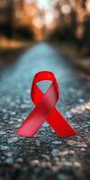 Red ribbon symbolizing awareness and support for HIV AIDS displayed in an abstract background photo
