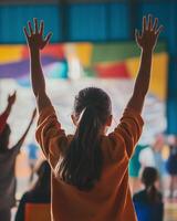 Back view of a child cheering enthusiastically at vibrant event with rainbow-colored lighting and energetic atmosphere photo
