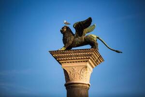 A statue of a lion with wings on top of a column photo