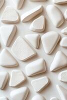 Geometric ceramic shapes in soft white and beige are arranged on a clean neutral surface. This modern abstract design creates a calming atmosphere with ample space for text overlay photo
