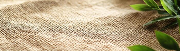 Close-up view of woven jute fabric in natural beige shades, complemented by small green plants along the edges, creating a stylish and rustic atmosphere for design projects photo