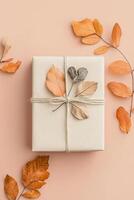 Handcrafted gift box features recycled paper adorned with dried autumn leaves and tied with cotton string, set on a soft pastel backdrop with space for text overlay photo