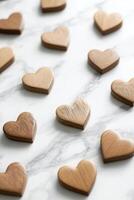 Small wooden hearts are arranged on a smooth white marble surface, illuminated by soft natural light. The large negative space invites text overlay for any romantic message photo