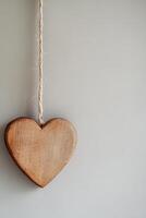 A wooden heart ornament hangs gracefully against a neutral light backdrop. This modern Nordic-style setting offers a stylish and minimalist aesthetic, perfect for text overlay photo