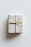This elegant gift box features a soft stone texture in light gray, beautifully tied with a thin gold string, showcasing a modern, stylish design perfect for special occasions photo