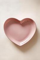 A soft matte pink heart-shaped ceramic plate with rounded edges rests on a smooth light background, highlighting its elegant minimalist design and creating ample space for text overlay photo