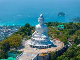 Aerial view of the Big Buddha statue in Phuket, Thailand, surrounded by greenery, with turquoise waters, distant islands, and boats in the background. photo