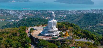 Aerial view of the Big Buddha statue on a hill in Phuket, Thailand, surrounded by greenery, with the Andaman Sea and islands visible in the background. photo