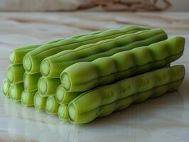 A close-up view of green beans stacked on a white marble surface photo