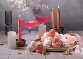 Pink and white heart-shaped meringues with lit candles and pink cocktails creating romantic atmosphere photo