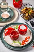 Two jars of red hot chili pepper sauce with blank label on a plate photo