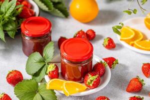 Homemade strawberry jam with orange slices and fresh strawberries photo