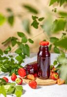 Fresh strawberry juice bottles surrounded by strawberries and mint leaves photo