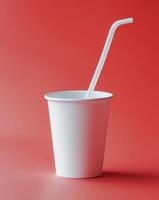there is a paper cup with a straw in it on a red surface photo