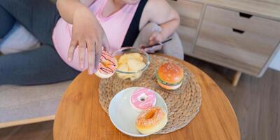 Indulging in sweets overweight individual enjoys desserts at home cozy environment close-up view on tempting treats photo