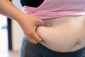 Weight struggles overweight individual examining fat around belly indoor setting lifestyle concept with dessert focus photo