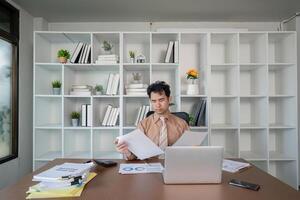 Businessman analyzing financial reports in a modern workspace, maximizing productivity with organized documentation photo