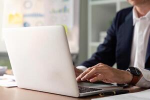 Senior executive analyzing data and reporting insights while working on a laptop in a corporate office photo