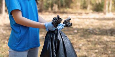 Volunteer holding a garbage bag in a forest, showcasing commitment to environmental cleanup and community service photo