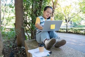 Woman with achondroplasia working on a laptop with coffee in a tranquil park photo