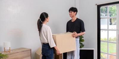 Content couple exchanging smiles while carrying a moving box in their new home, celebrating teamwork photo
