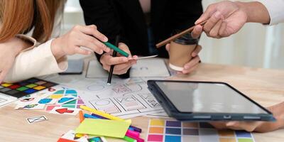 Collaborative UX UI team examining design notes and sketches while engaging in a creative discussion photo