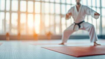 Martial artist practicing stance on mats in bright dojo setting, showcasing focus and discipline. warm sunlight enhances atmosphere of training and dedication photo