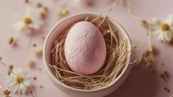 Beautifully decorated pink Easter egg nestled in a natural straw nest with delicate white flowers on a soft pastel background photo