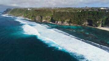 Scenic landscape with cliffs on coastline with ocean and powerful waves in Bali. Aerial view of Melasti beach video