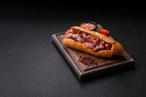 Delicious juicy hot dog with sausage, bacon, sauce, salt and spices qa photo