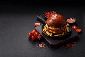 Delicious burger with beef , fried egg, bacon, herbs, sauce, salt and spices photo